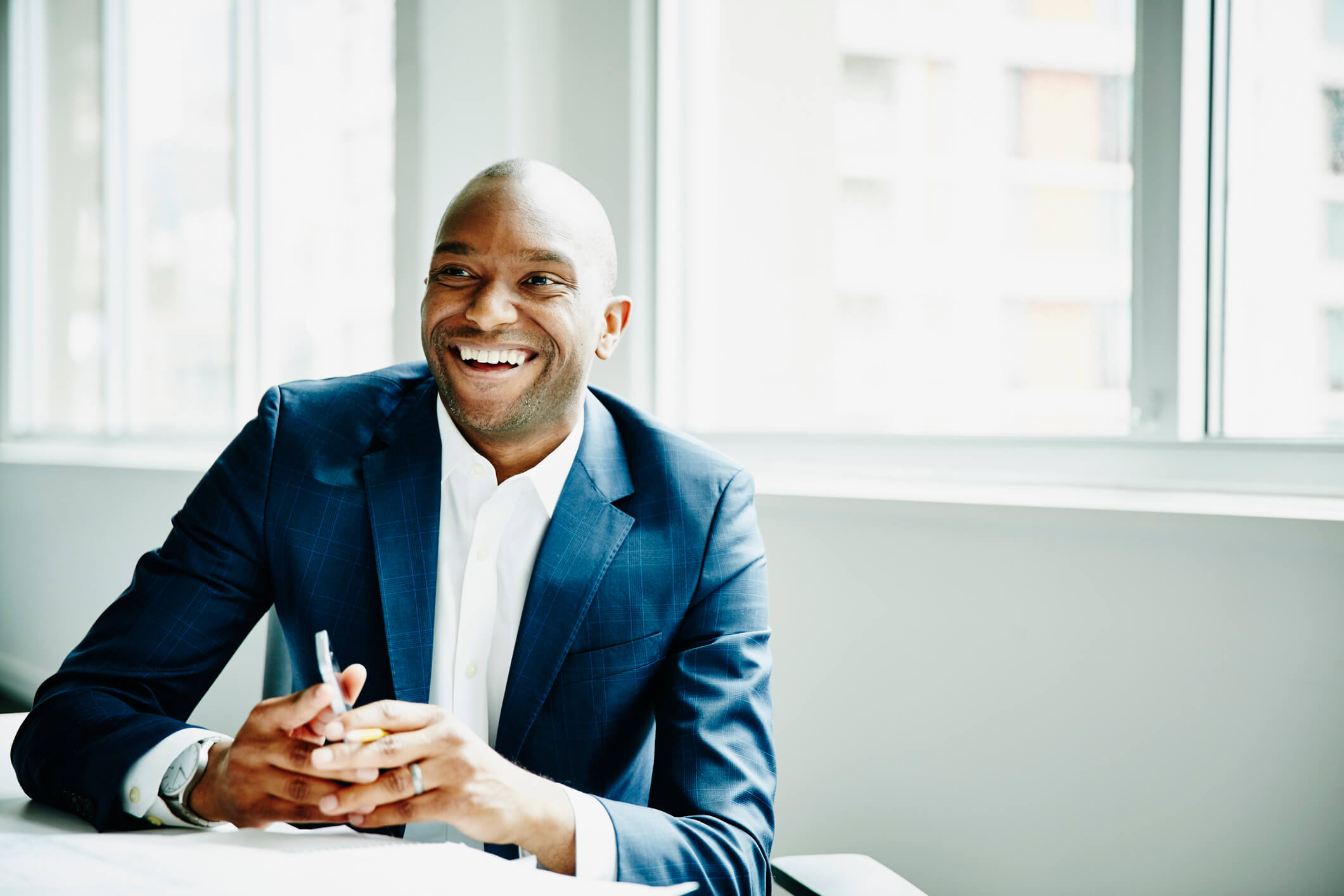 man smiling past camera in blue suit discussing professional goals